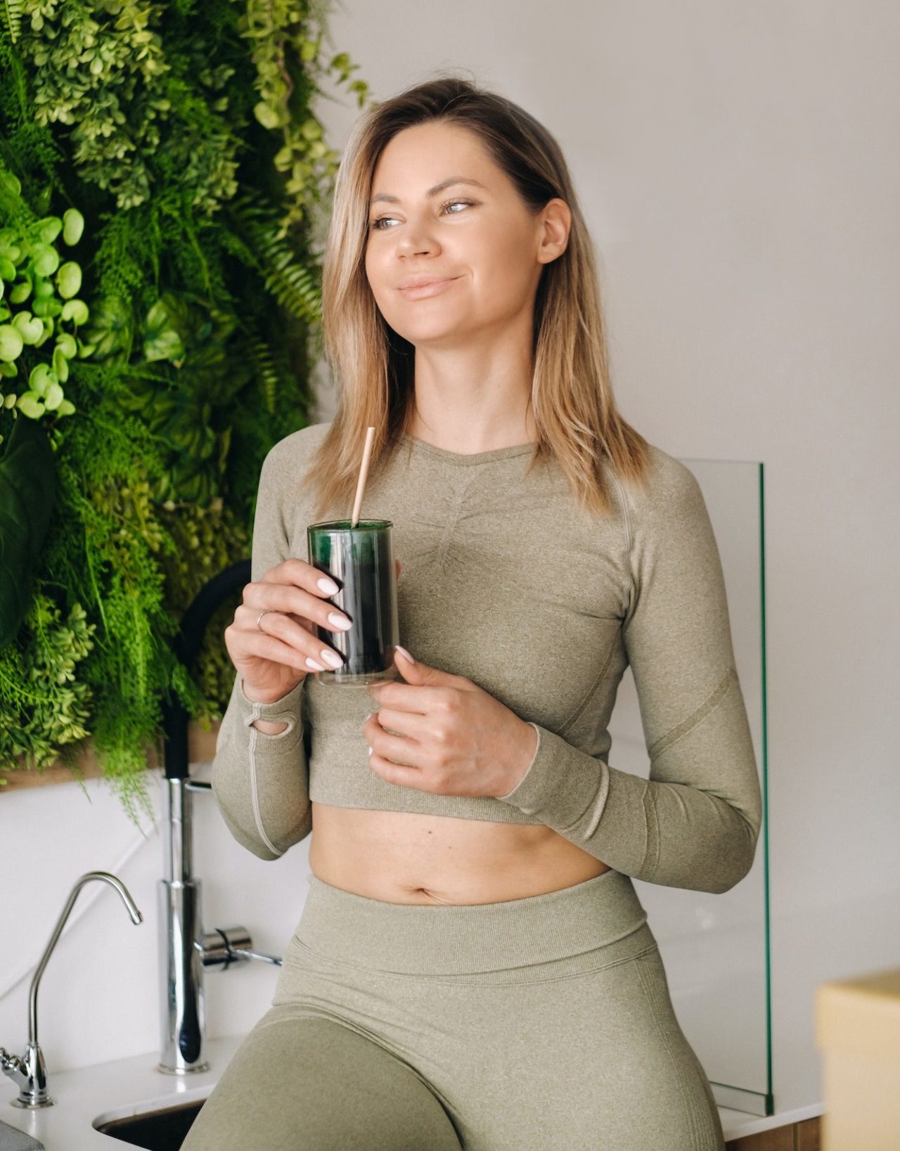 a sporty woman in sportswear holds a smoothie cocktail in her hand the concept of healthy eating e1682306162902